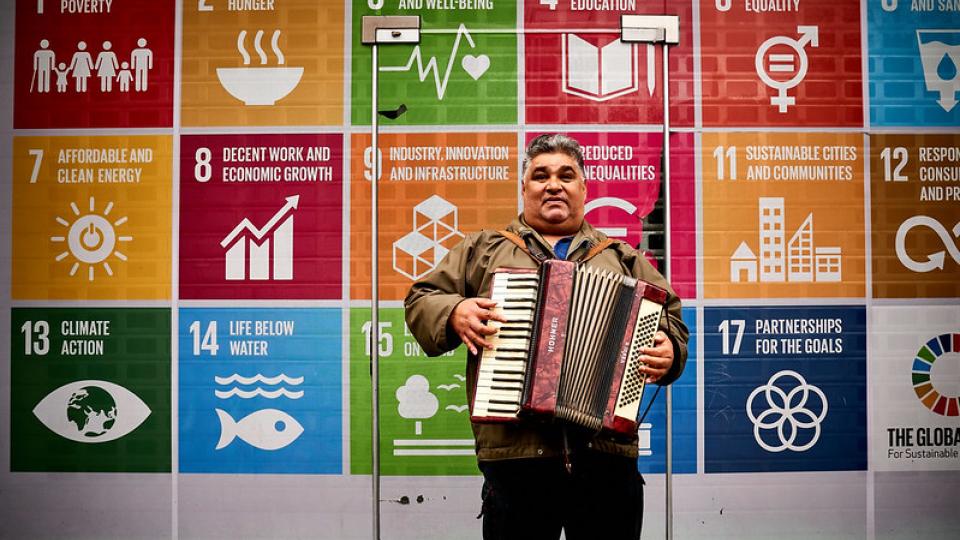 Muzikant speelt voor plakkaat met SDG's Muzikant speelt voor plakkaat met SDG's